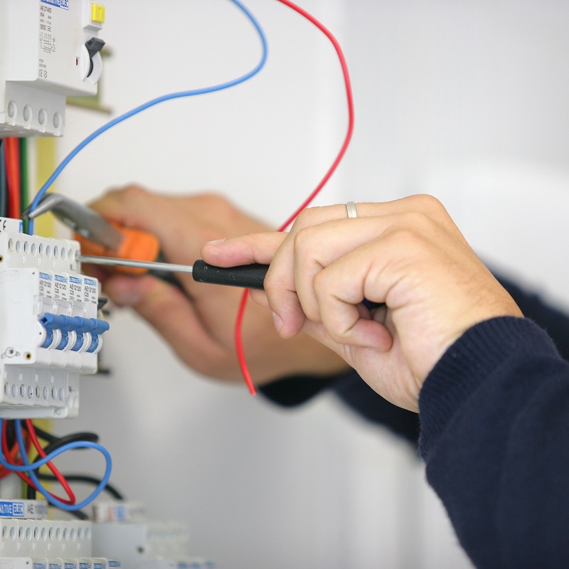 Électricien professionnel travaillant sur un tableau électrique Électricien raccordant des fils électriques dans un tableau avec disjoncteurs AE12120 C20.